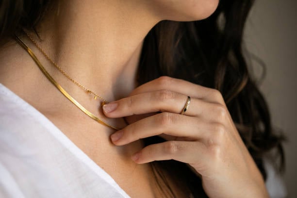 A gold-plated name necklace is a personalized piece of jewelry with a person's name or initials on it. 